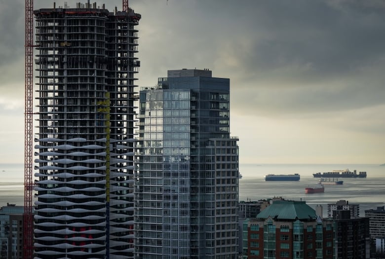 A condo tower is seen under construction in downtown Vancouver as freighters sit at anchor on English Bay.