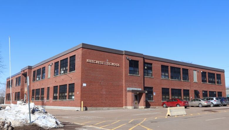 A two-storey red brick building with several cars parked outside. 