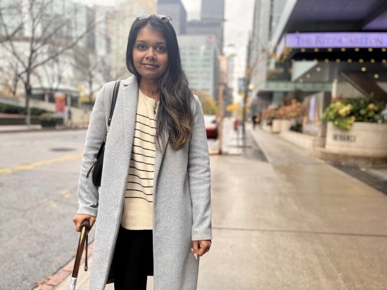 A woman holds a cane out front of the Ritz Carlton hotel in downtown Toronto.