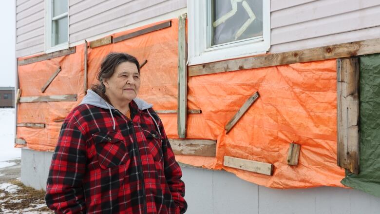 A Glace Bay woman stands in front of her home that was badly damaged by post-tropical storm Fiona in September 2022. 