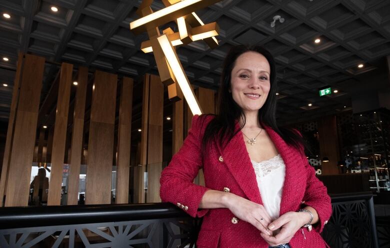 A woman leans against a railing in a restaurant.