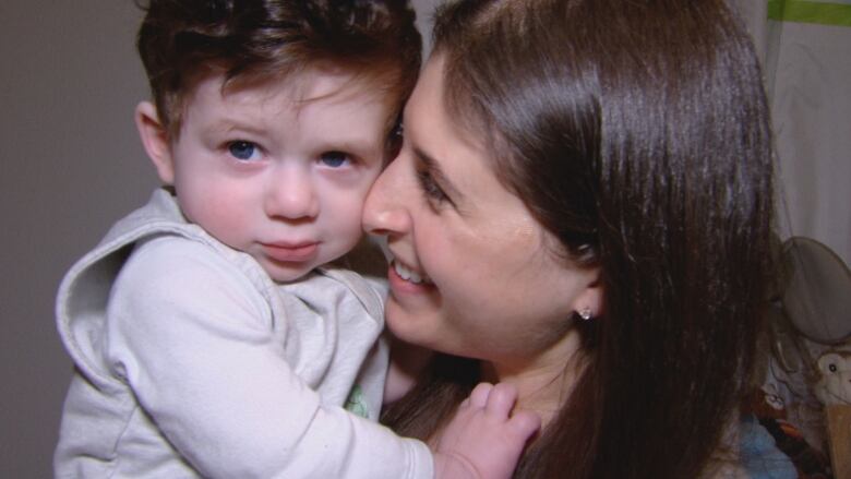 Close up photo of Alanna Handleman holding her son Chase. Chase looks at the camera, while Handleman's face is in profile, smiling at Chase with her nose pressed to his cheek. 