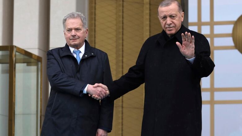 Two men shake hands.