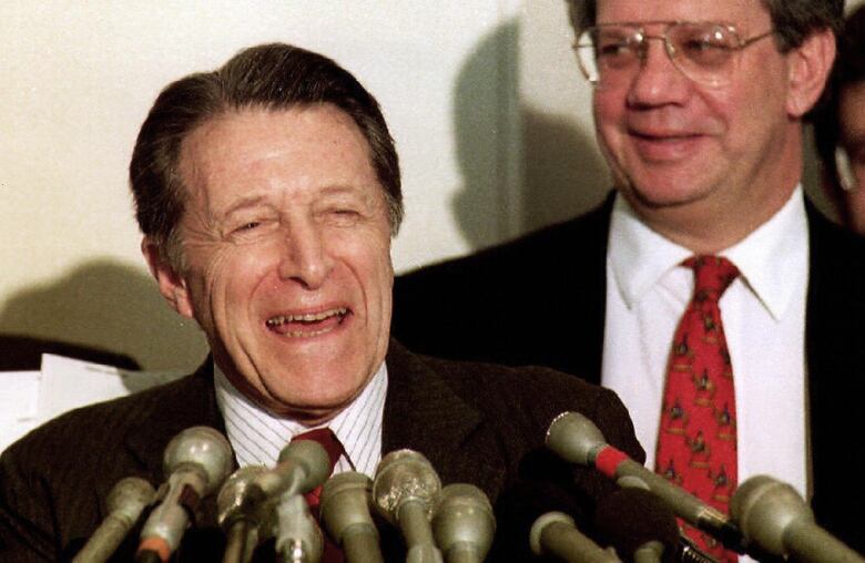 A man appears to laugh while in front of microphones.