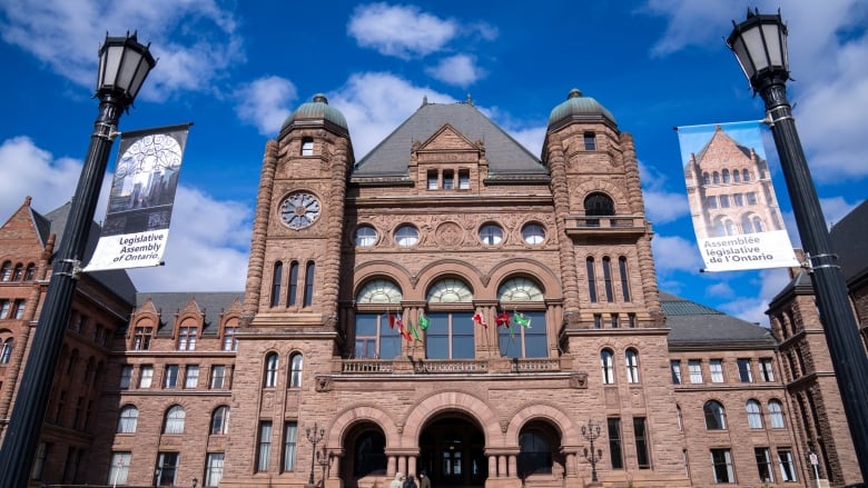 The front of the Ontario Legislature historic building is pictured in downtown Toronto against a blue sky.