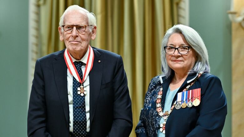 A man and a woman, both wearing medals, stand side-by-side.