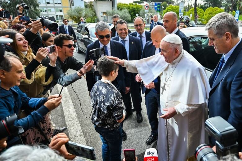 The Pope touches a boy on the head.