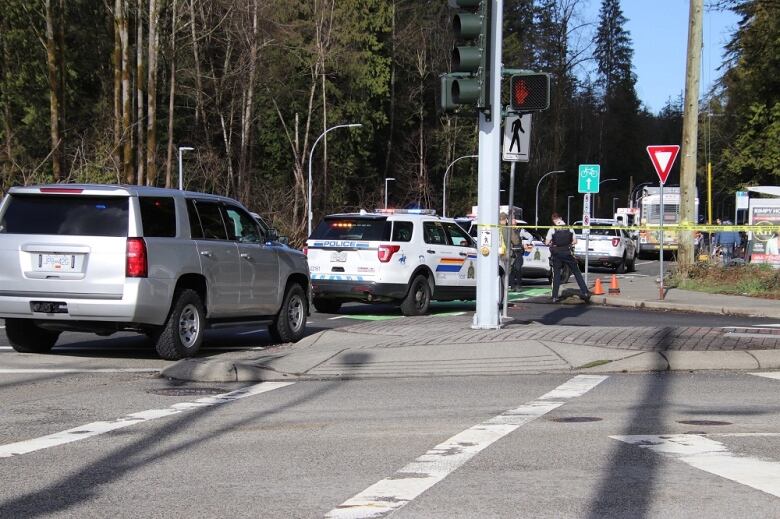 An intersection on a highway is seen filled with police vehicles, with a bus visible in the background.