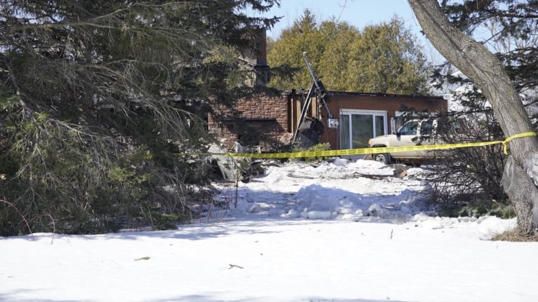 The outside of a burned house, with police tape around the scene. 