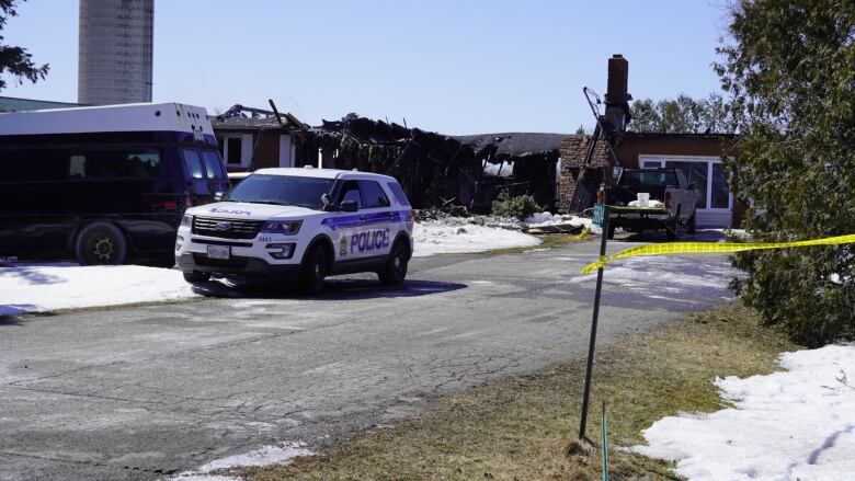 The outside of a house partially destroyed in a fire, with a police car in front. 