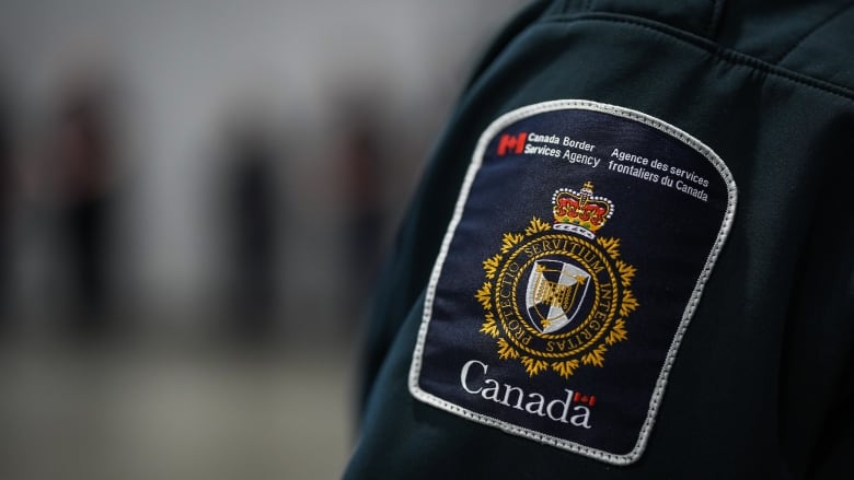 A patch is seen in a close-up shot of the shoulder of a Canada Border Services Agency officer's uniform.