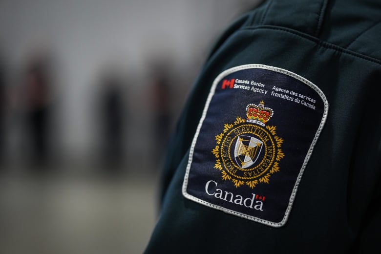 A patch is seen in a close-up shot of the shoulder of a Canada Border Services Agency officer's uniform.