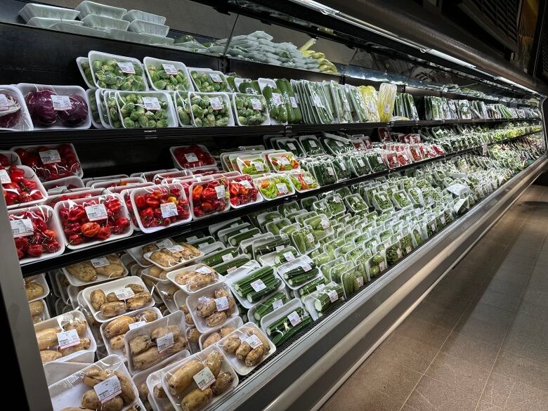 Grocery store produce aisle where all products are packaged with plastic and thermal labels. 