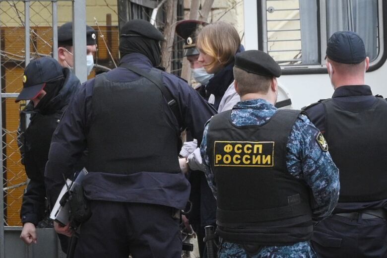 A woman escorted by officers enters a court building in Moscow.