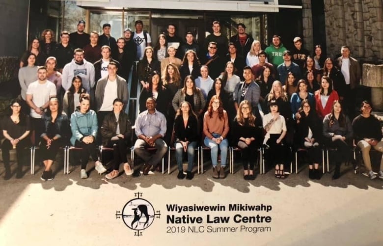 A class photo of many law students posed in front of a building