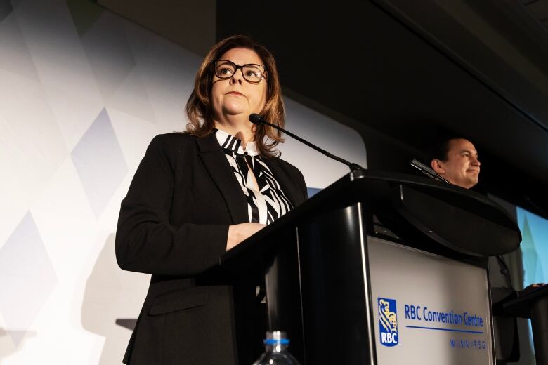 Woman with serious expression stands at a podium.