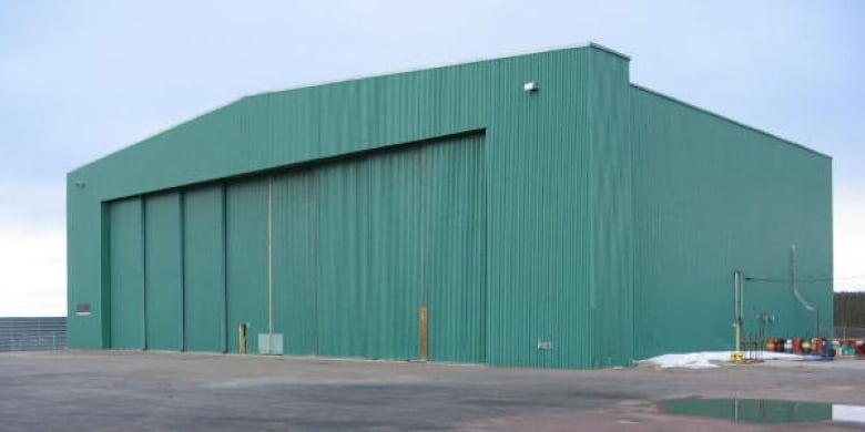 A large green airplane hangar is seen from the outside.