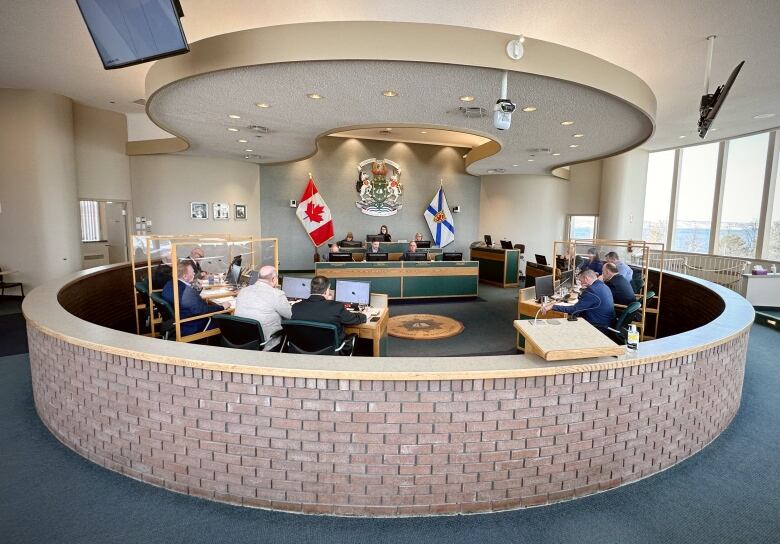 Picture of a council room with people sitting around a circular table.