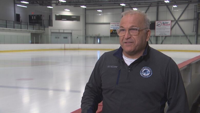 A coach is talking near an ice surface. 