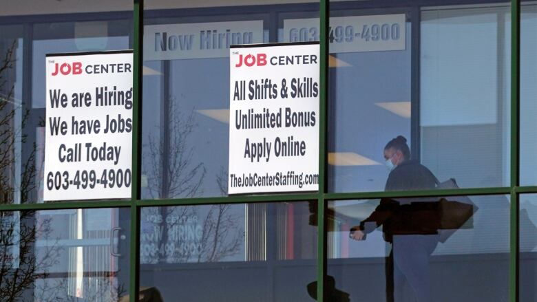 A woman walks by signs advertising an employment agency.