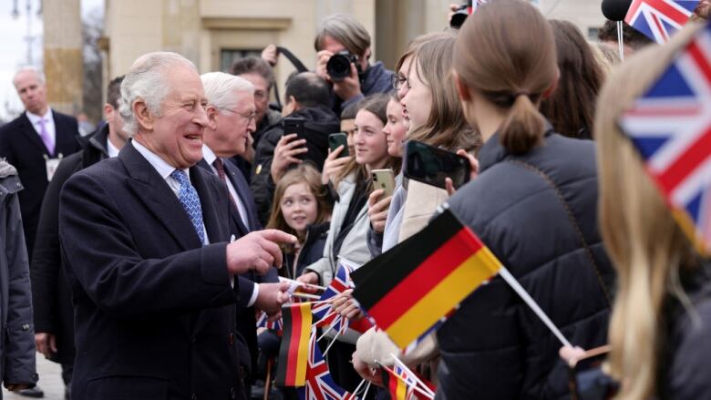 A person greets people lineup and holding flags of Germany and the U.K.