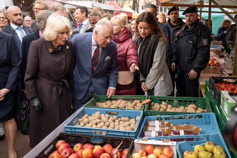 People look at produce in a market.