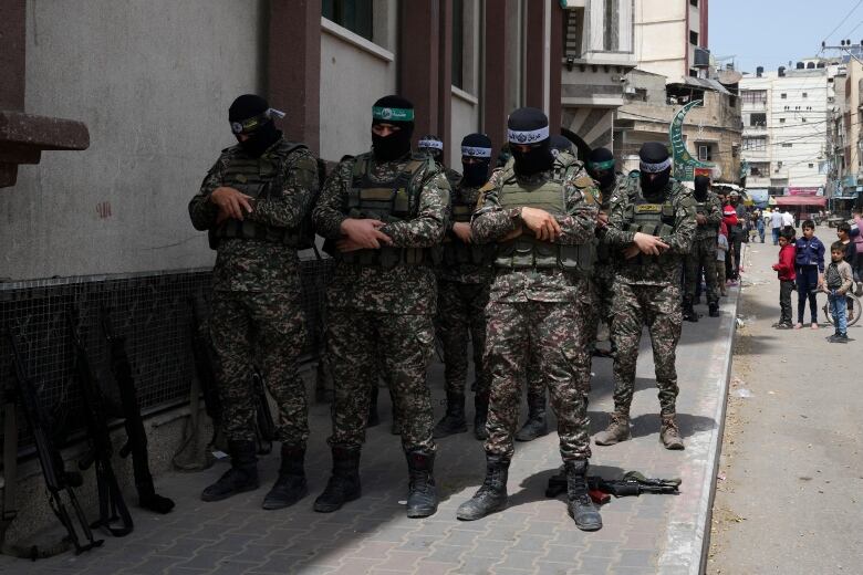 Masked men in combat gear pray.