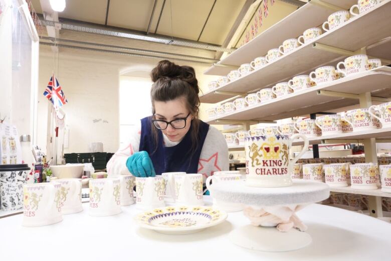 A person working in a pottery factory works on a mug.