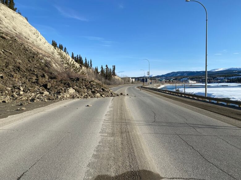 The photo shows a portion of the road covered with rocks and mud after a landslide