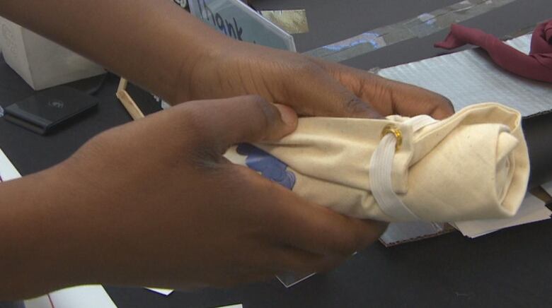 A pair of hands are seen rolling up a tote bag.