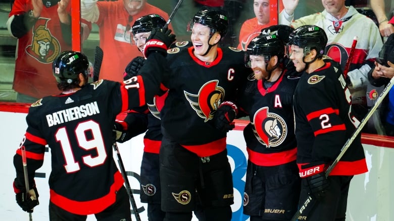 Five hockey players celebrate a goal on home ice.