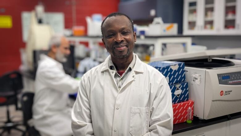 A man in a lab coat poses in a laboratory in Charlottetown