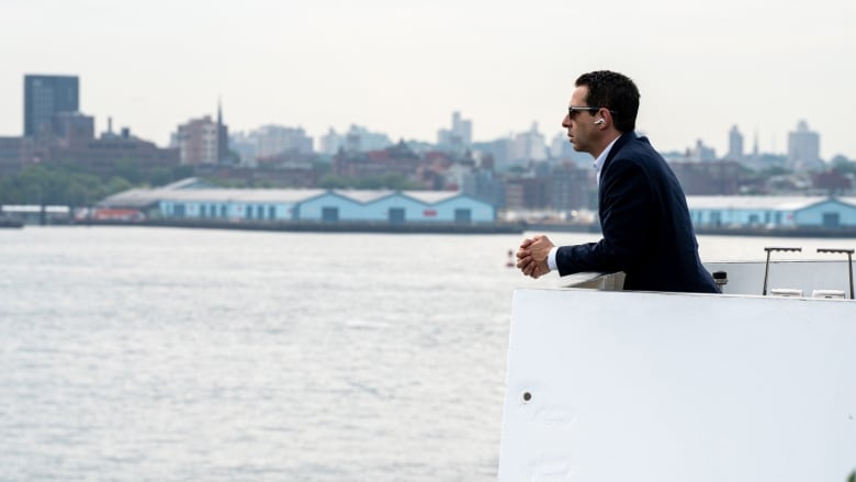 A man wearing Airpods rests his elbows on the edge of a yacht.