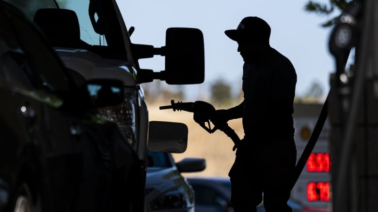 The silhouette of a man pumping gas is shown.