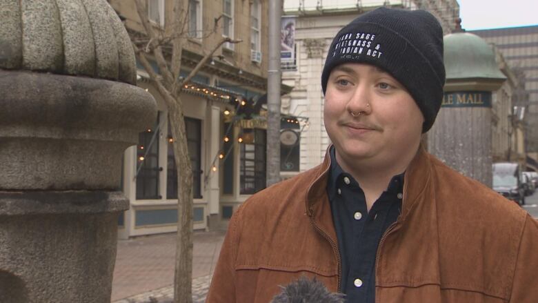 A boy wearing a black beanie and brown jacket. 