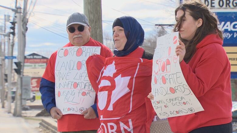 Three people wearing red holding signs and flags