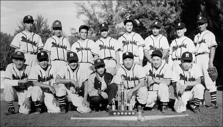 A group of men in baseball uniform are pictured lining up for family photo.