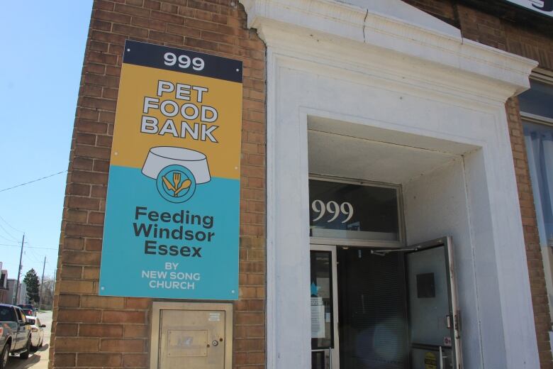 A sign on the corner of a building advertises a pet food bank. 