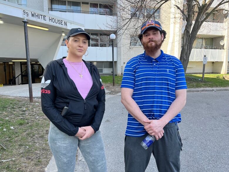 A man and a woman stand outside an apartment building.