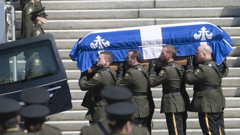 Police officers carry a casket near the steps of a church.