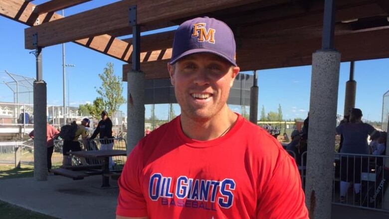 A man in a baseball uniform grins at the camera. 