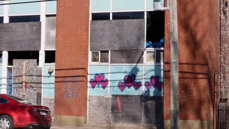 A derelict building within the Cape Breton Regional Municipality is shown with boarded up and broken windows. 