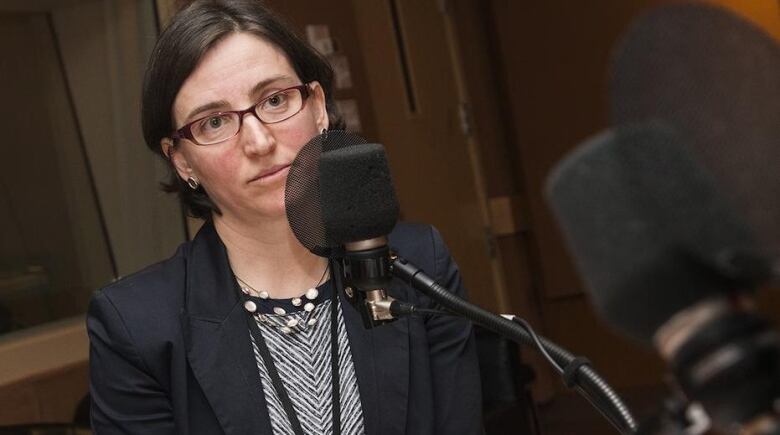 A woman sits in front of a radio microphone.  