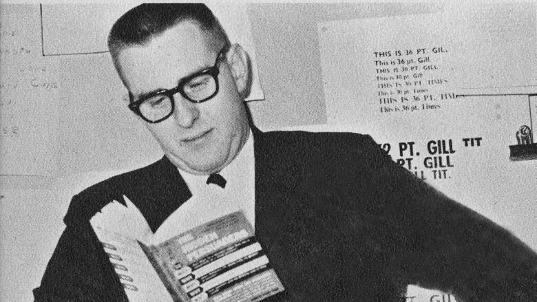 Black and white photo of man holding book. Printed under the photo are the words 