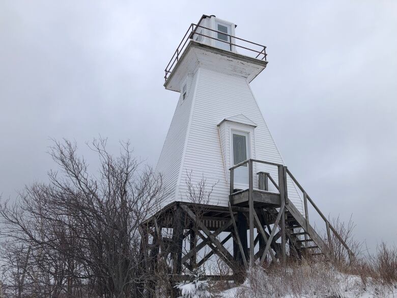 photo of white lighthouse with steps leading to door