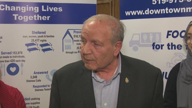 A man wearing a suit speaks to a press conference in Windsor. 