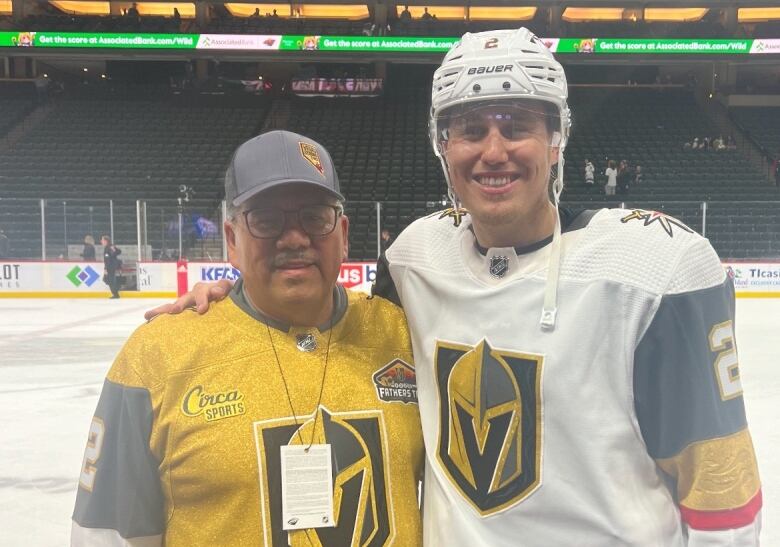 Two people stand in jerseys at a hockey game.