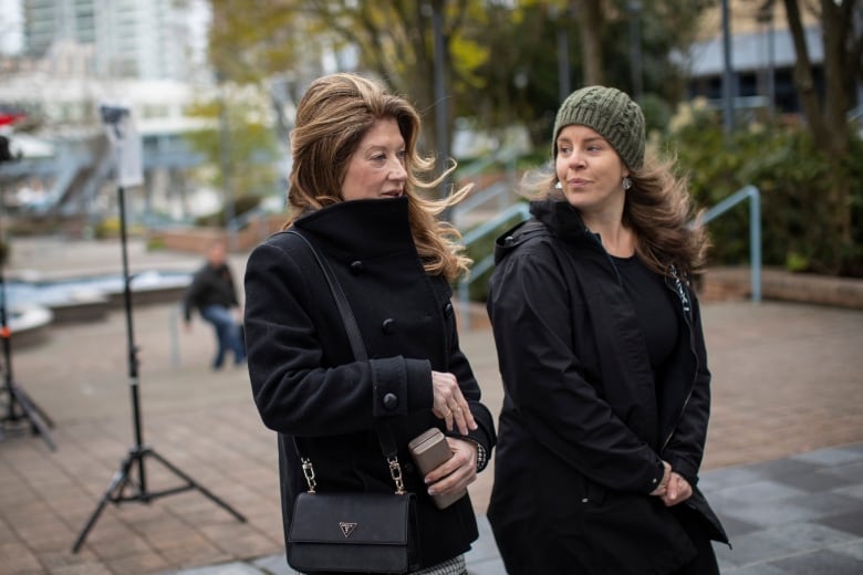 A woman with long curled hair walks into an office building.