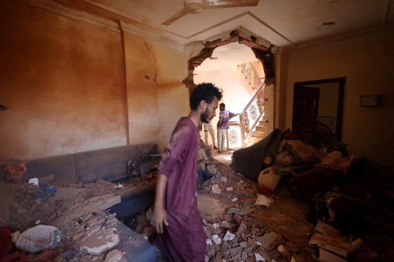 A man walks through the rubble in a destroyed home.