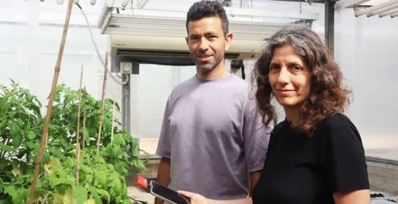 Two professors stand in front of plants.